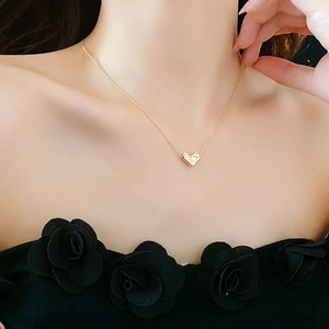 Detail view of heart pendant gold necklace worn by a model with natural lighting