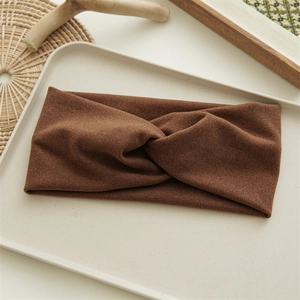 Detail of a wide brown twisted velvet headband displayed on a beige jewelry tray
