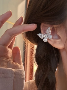 Close-up of elegant silver butterfly ear cuff with sparkling zircon on person's ear