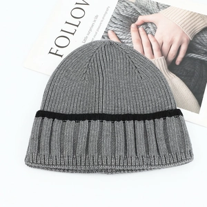 Detailed close-up of soft ribbed grey knit beanie with black stripes on white background