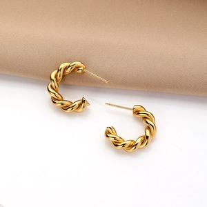 Macro shot of gold twisted hoop earrings with a polished C-shape design and glossy finish