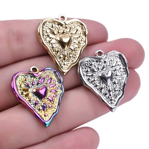 Three heart charms in gold, silver, and rainbow steel with embossed sunburst texture