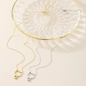 Minimalist cat pendant necklaces in gold and silver finishes on a glass plate