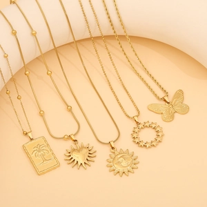 Golden stainless steel necklaces with sun heart and butterfly pendants on beige studio set