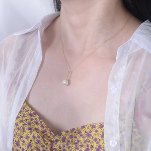 Close-up of a s925 silver gold necklace with large white pearl and zircon pendant on neck