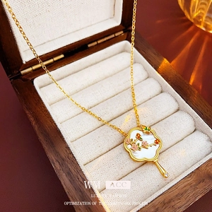 Macro shot of gold-plated fan necklace with mother of pearl and floral enamel details