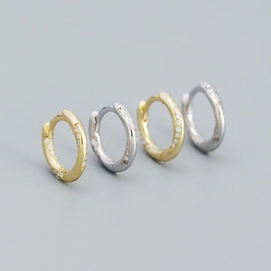 Macro shot of 925 silver hoop earrings with diamond accents in gold and silver finish