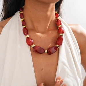 Close-up of red irregular acrylic beads and golden spacers on a chunky statement necklace