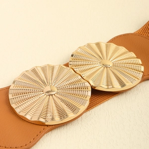 Detail of brown elastic waist belt with textured gold circular buckles on beige background