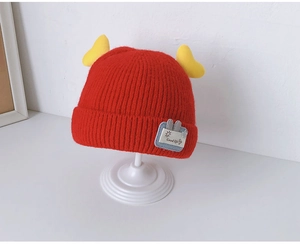Detail of red knit baby hat featuring cute yellow horns and Good Life rabbit patch