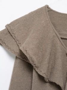 Détail d'un haut en maille taupe avec bords à volants et motifs pointelle ajourés