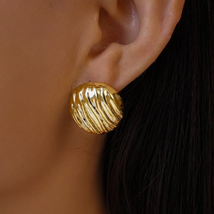 Gros plan de boucles d'oreilles rondes dorées en acrylique avec surface texturée