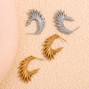 Macro shot of geometric spiral earrings with C-shape texture in gold and silver finish