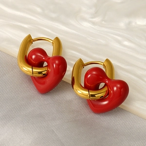 Detailed shot of 3D red heart pendants on golden U-shaped earrings on stone background