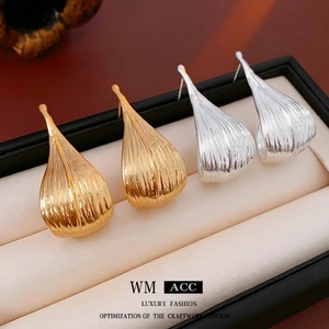 Artistic gold and silver leaf earrings with textured vertical stripes in jewelry box