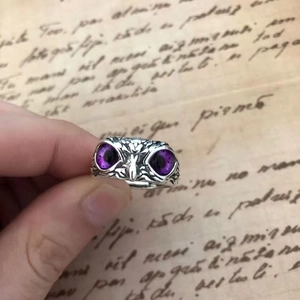 Vintage silver owl ring with purple gem eyes on a retro manuscript background