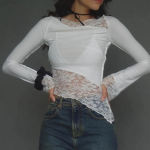 Detailed shot of white lace patchwork top with asymmetric hem and slim fit sleeves