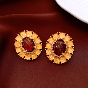 Detail of vintage gold-toned oval earrings with red agate center on red silk fabric