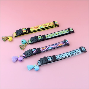 Detailed view of colorful bohemian plaid cat collars with tassels and bells on pink base
