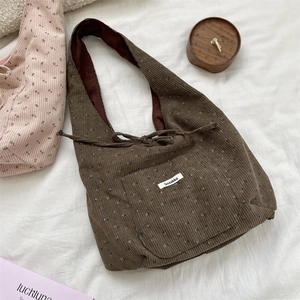 Detailed view of brown corduroy tote bag with white floral patterns and Sozakka label