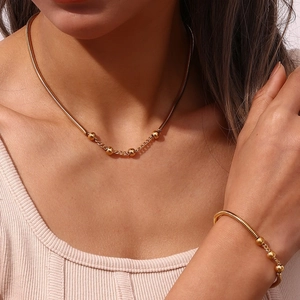 Fashionable golden stainless steel jewelry set with snake chain and beads on a model