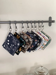 Detail showing eight embroidered cotton linen coin purses hanging with metal clips