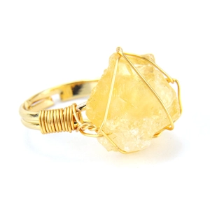 Detailed close-up of handmade wire-wrapped ring with irregular yellow raw stone