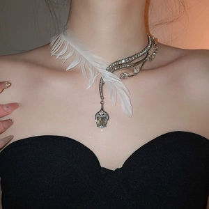 Gros plan d'un ras-du-cou argenté asymétrique avec plume blanche et strass brillants