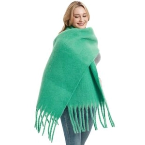 Dettaglio di sciarpa in maglia verde con consistenza morbida e lunghe nappe a frangia