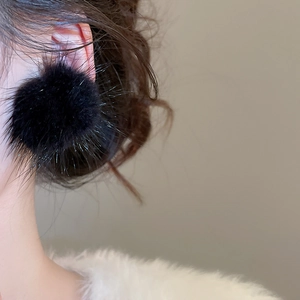 Gros plan de boucles d'oreilles pompon en résine noire portées par un mannequin