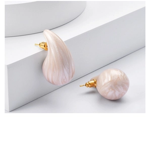 Detailed close-up of chunky teardrop earrings with pink marble texture on white stand
