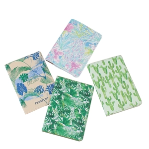 Flat lay of four passport covers with tropical leaf, floral, and cactus prints on white background