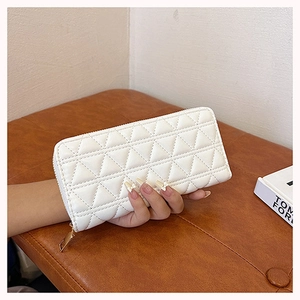 Close-up of hand holding a white quilted long wallet with elegant diamond stitching