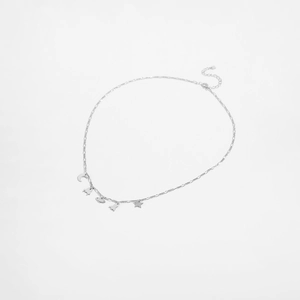 Detail of silver S925 necklace featuring star, moon, and rocket charms on white background