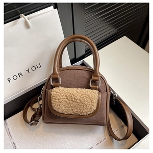 Close-up of brown suede handbag featuring beige faux shearling pocket and silver hardware
