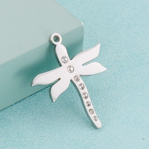 Macro detail of a silver dragonfly pendant with sparkling zircons on a blue background