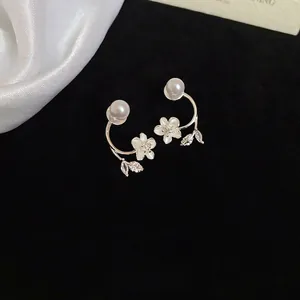 Silver flower stud earrings with pearls and zircon crystals on black velvet background