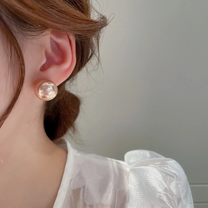 Close-up of elegant gold ball stud earrings worn by a model in a minimalist style