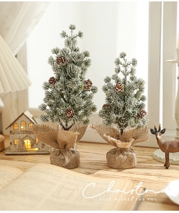 Detail of snowy mini Christmas trees with pine cones and rustic burlap wrapped base
