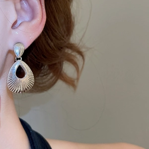 Detailed close-up of silver teardrop hollow earrings with radiant textures on ear