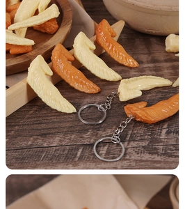 Macro detail of realistic chicken wing keychains showing texture on a wooden table