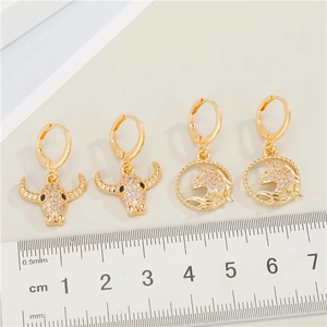 Gold unicorn and bull head leverback earrings with pavé zircons and a scale reference
