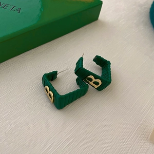 Detail of dark green square earrings with golden B logo on a brand gift box