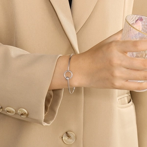 Close-up of minimalist silver stainless steel bangle with geometric ring and bead detail