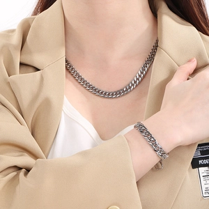 Close-up of a men's silver stainless steel Cuban link necklace and bracelet set on model