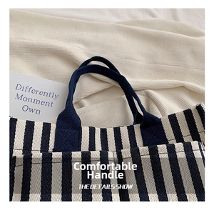 Detail of comfortable dark blue woven handles on blue and white striped canvas tote bag
