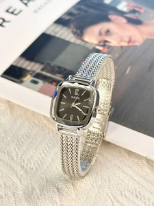 Close-up of square black dial watch with silver mesh strap on minimalist background