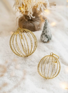 Detail of golden hollow wire Christmas ball ornaments with glitter on a snowy background