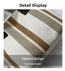 Close-up of striped canvas tote bag showing stitching and brown leather handle attachment
