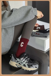 Détail des chaussettes montantes rouge foncé avec lettre C et leggings gris